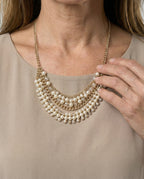 Close view of the khaki dress neckline beneath a layered necklace.