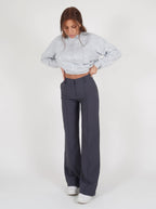 Grey trousers viewed from the front with hands near the waistband.
