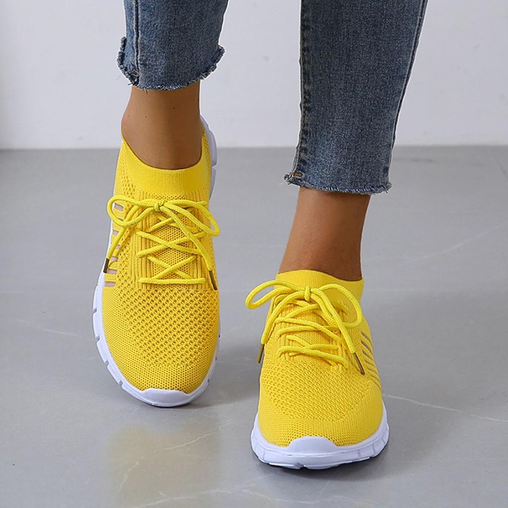 Yellow trainers shown from above while worn with jeans.