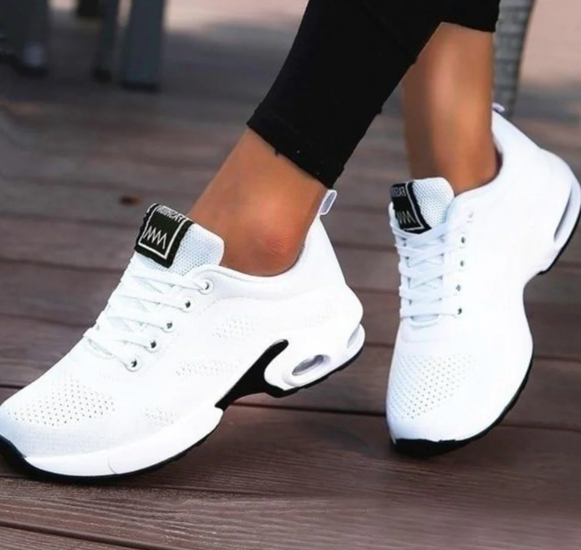 White trainers with black contrast panels and oval heel sections.
