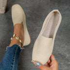 Beige textured slip-on flats, with one shoe held to show the opening and insole.