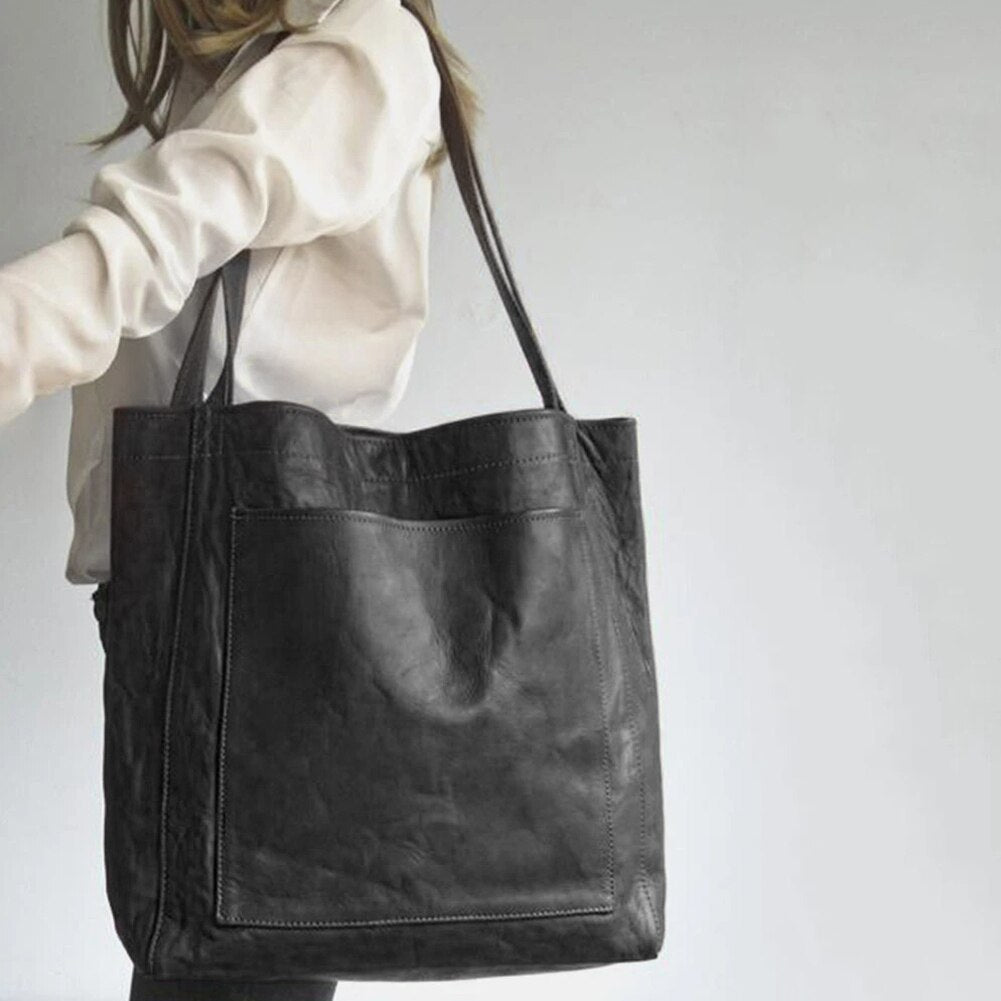 Black shoulder tote worn with a white blouse.