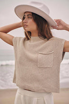 Beige short-sleeve knit top with a chest pocket worn above cream trousers.