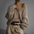 Beige fluffy cardigan with long sleeves, worn loosely over one shoulder.
