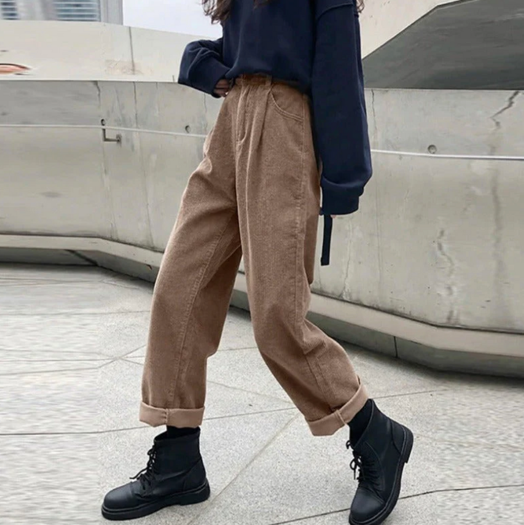 Grey-brown trousers worn with a dark loose top and boots.