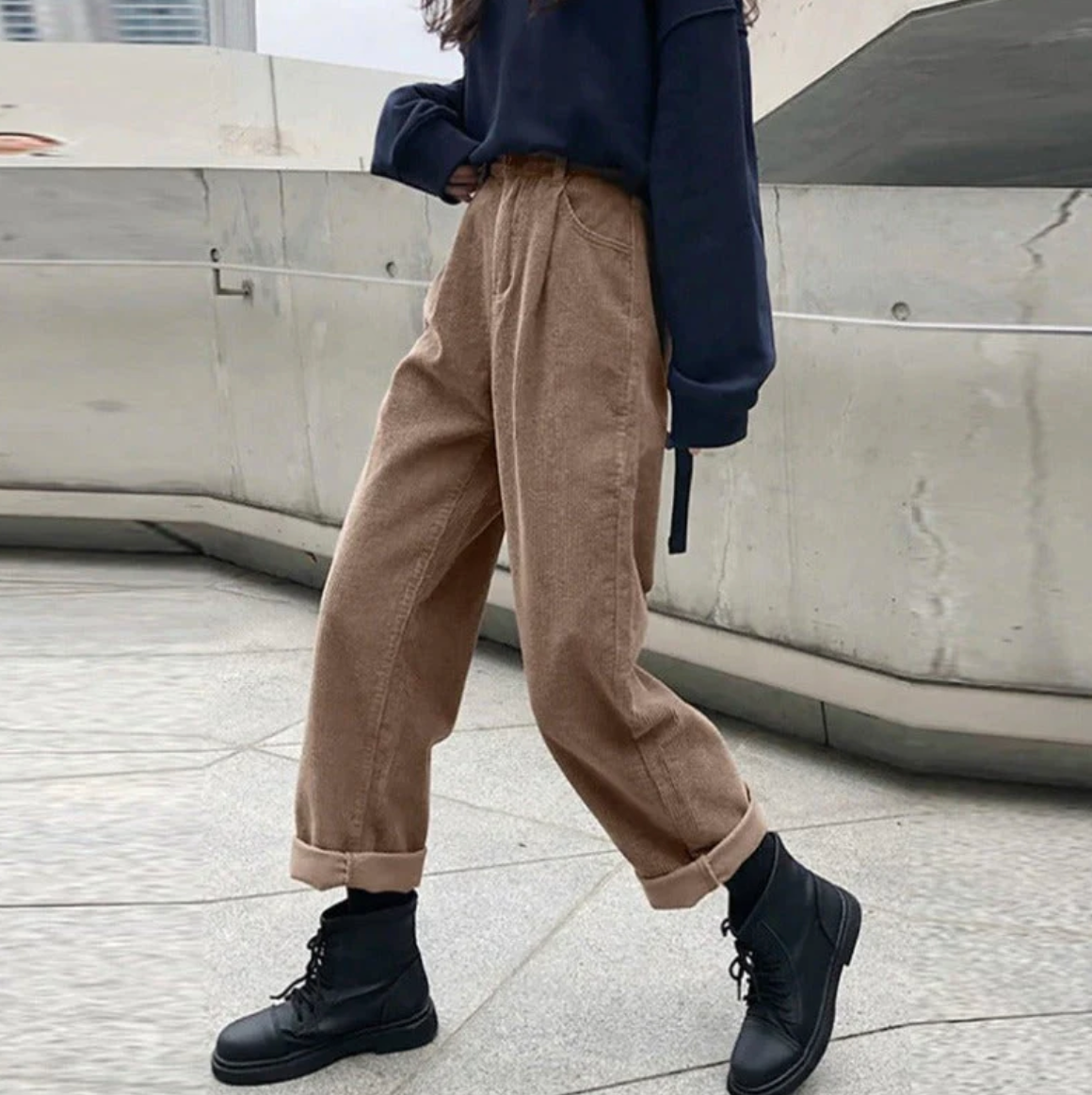 Grey-brown trousers worn with a dark loose top and boots.