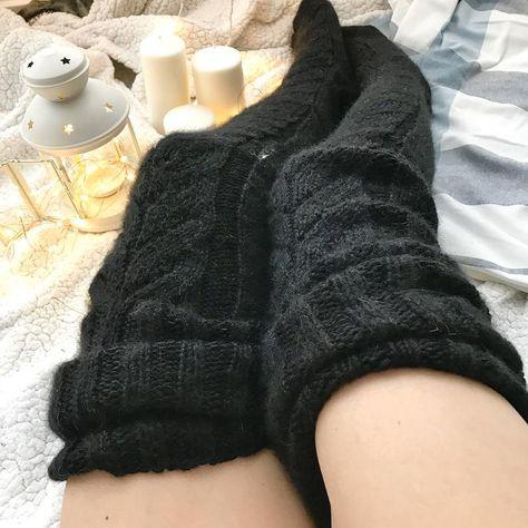Black long knitted socks worn while resting beside candles.