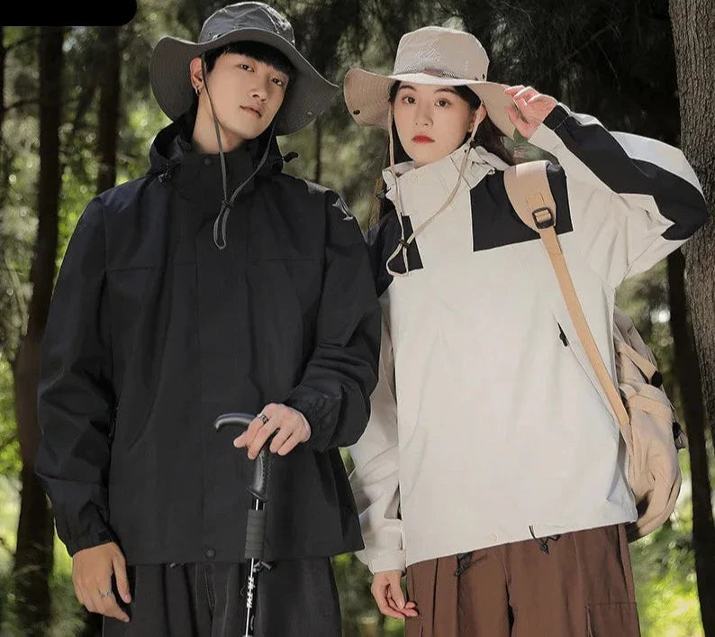 Two people wearing black and pale hooded jackets outdoors.