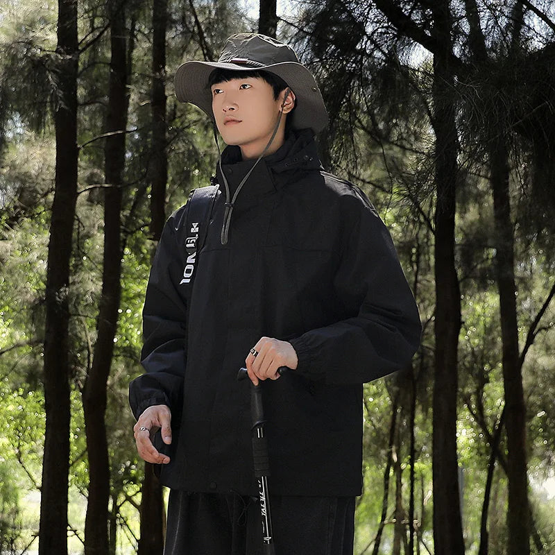 Black jacket worn outdoors with a hat and walking pole.