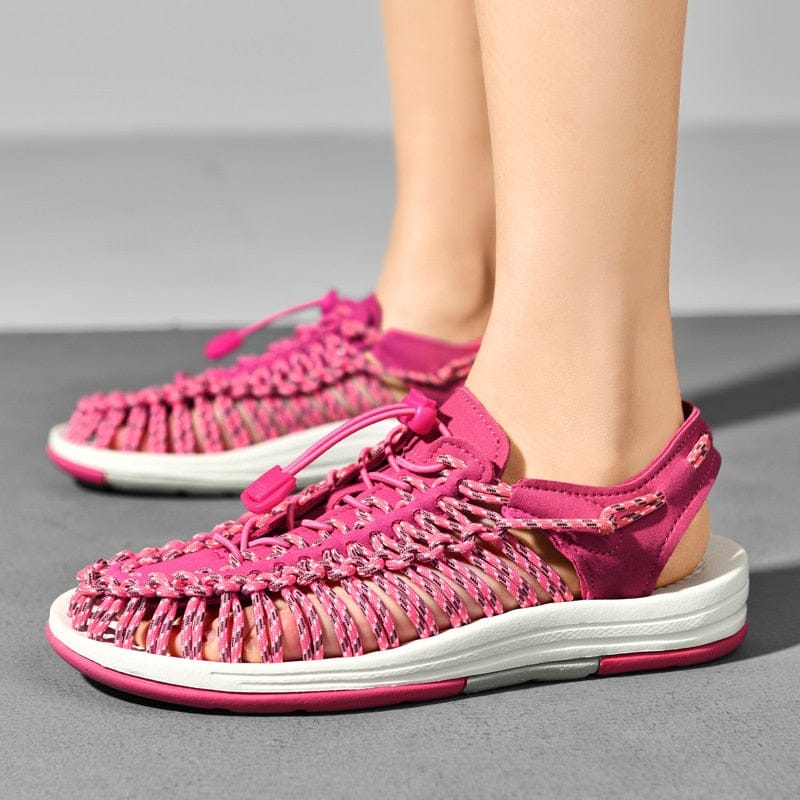 Pink cord sandals with toggle laces and white soles, worn on feet.