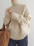 Cream-toned roll-neck sweater with ribbed cuffs and hem, worn with jeans.