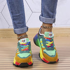 Green colourblock sneakers with rainbow laces, shown from above.