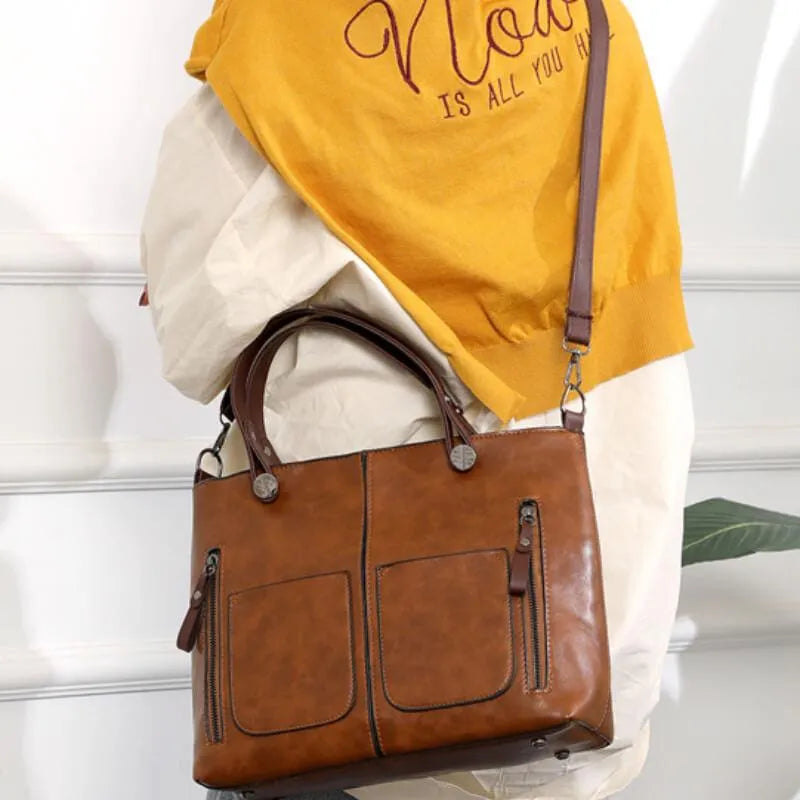 Brown handbag worn across the body with the long strap.