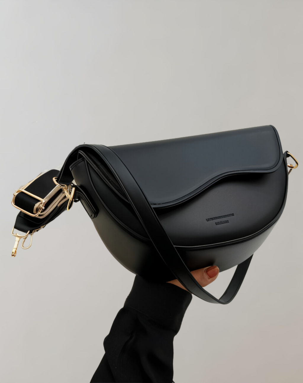 Black structured shoulder bag with a curved front flap.