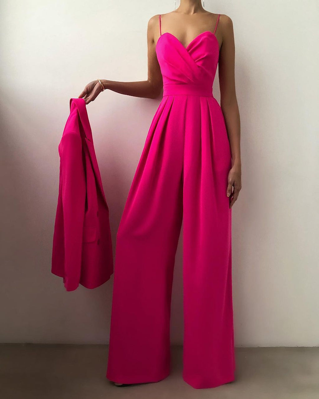 Rose-red jumpsuit shown with a matching jacket in hand.