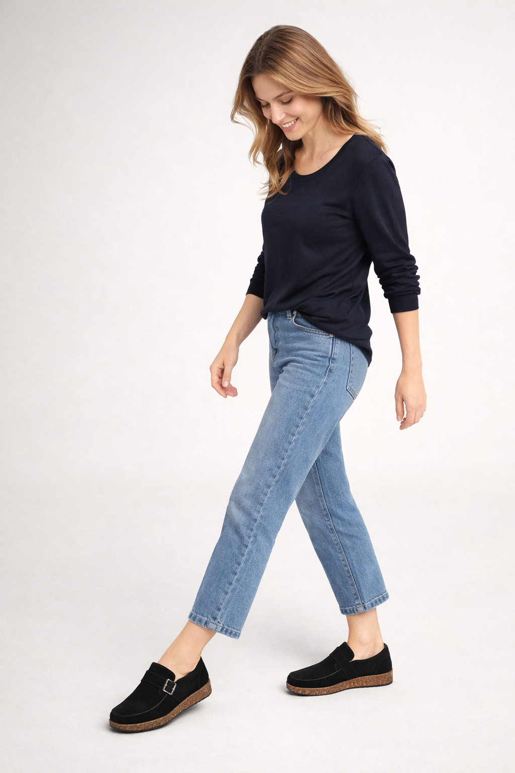 Black clogs worn with cropped blue jeans while walking.