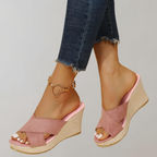 Pink crossed-strap wedge sandals with pale woven-look heels.