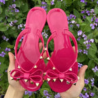 Rose red sandals with bows and studded toe-post straps.