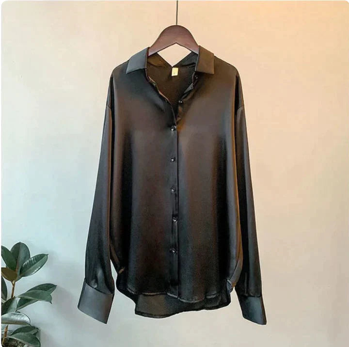 Black shirt with a button-through front, pointed collar and long cuffed sleeves.