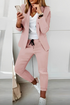 Pink open-front blazer and drawstring trousers shown with a contrasting top and white trainers.