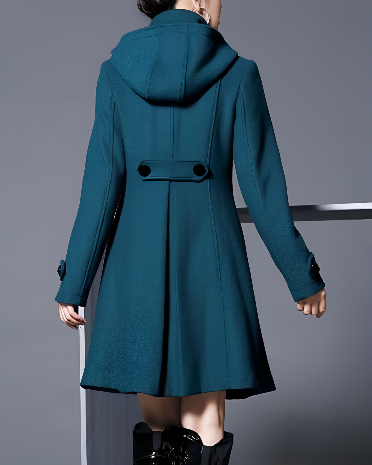 Rear view of the teal-toned coat showing its hood and buttoned waist tab.