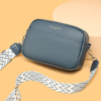 Blue bag with a pale patterned strap and top zip.
