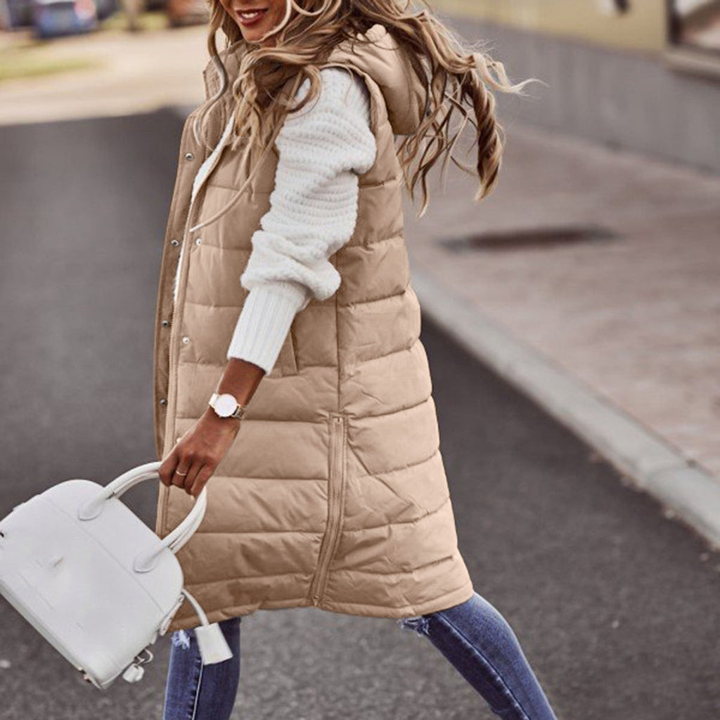 Khaki long quilted gilet worn over a white jumper.