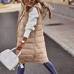 Khaki long quilted gilet worn over a white jumper.