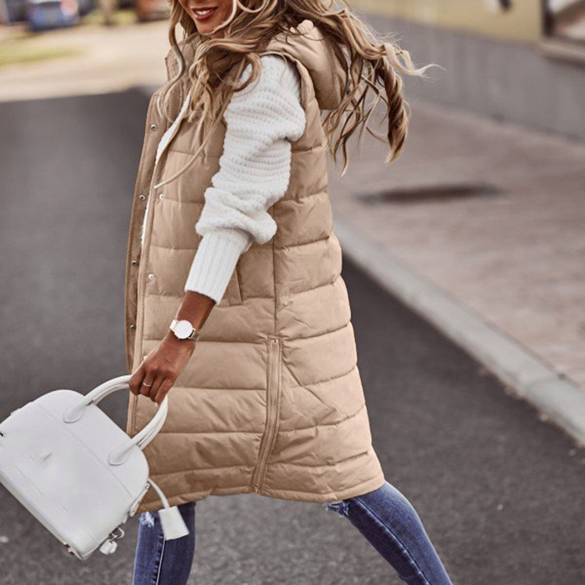 Khaki long quilted gilet worn over a white jumper.