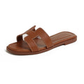 Brown flat slide sandal with a cut-out strap, pale stitching and embossed insole lettering.