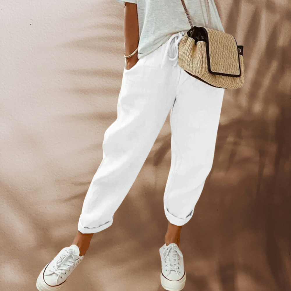 White relaxed trousers worn with white trainers.