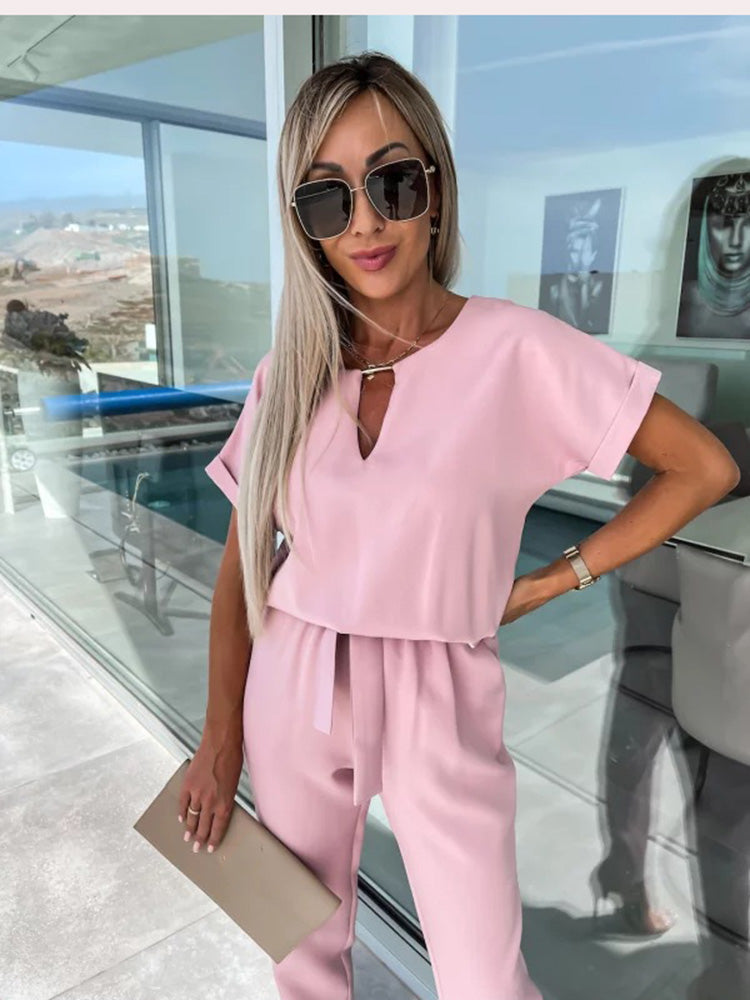 Pink jumpsuit with a loose upper section and front neckline opening.