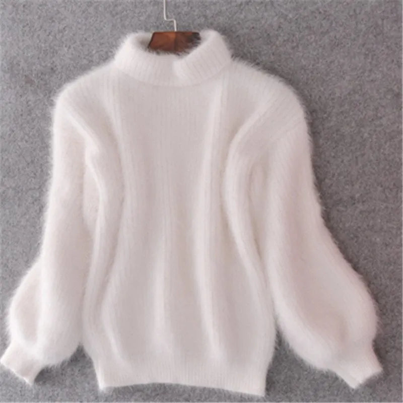 White fuzzy jumper on a hanger showing its high neck and full sleeves.