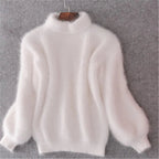 White fuzzy jumper on a hanger showing its high neck and full sleeves.