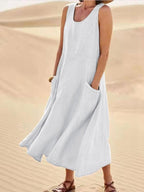 White sleeveless dress with a loose long skirt and patch pockets.
