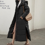 Black long quilted hooded coat with side pockets, shown being worn.