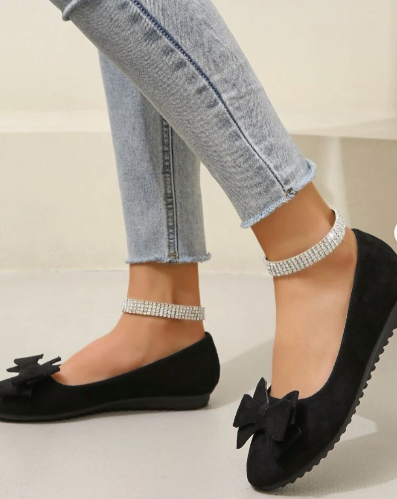 Black bow-front flats with low textured soles.