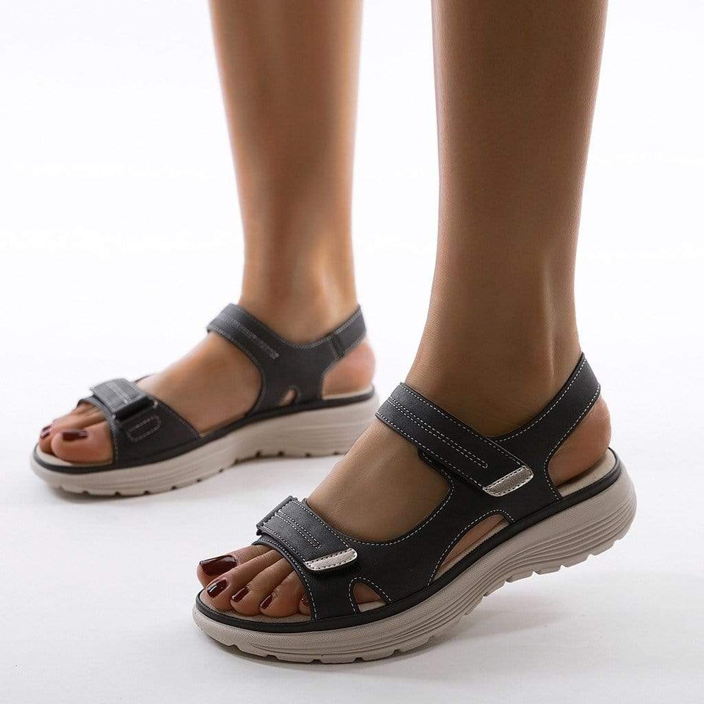Dark blue sandals viewed from the side with raised soles and open heels.