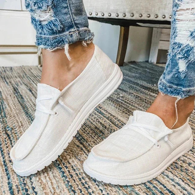 White lace-up shoes with rounded stitched toe panels.