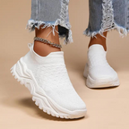 White trainers shown worn from the front, with raised ankle openings and textured uppers.