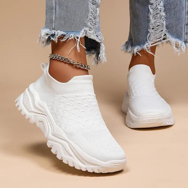White trainers shown worn from the front, with raised ankle openings and textured uppers.