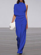 Blue jumpsuit with a high neckline and soft folds at the waist.