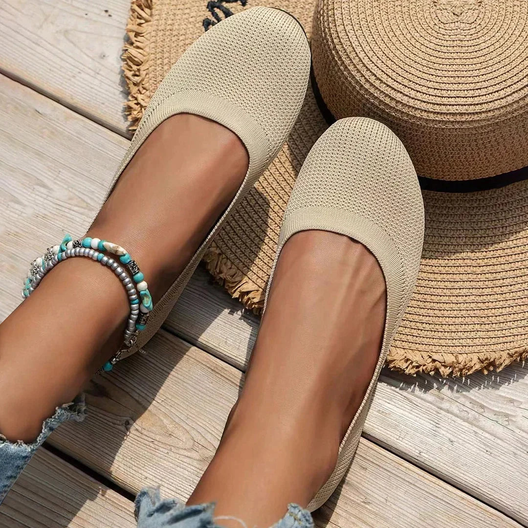 Beige rounded-toe flats shown beside a woven hat.