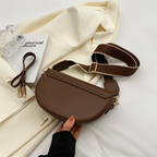 Back view of a brown shoulder bag with straps laid beside it.