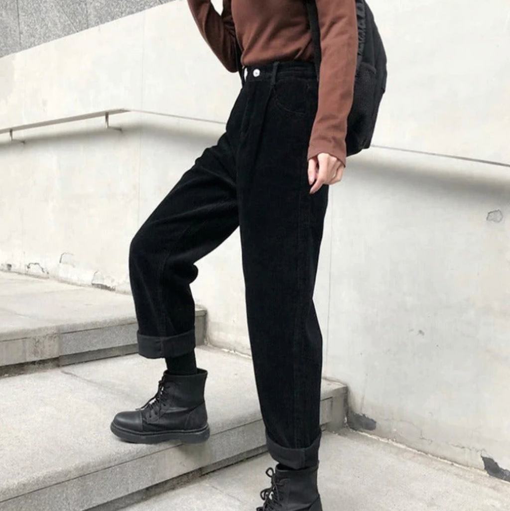 Black ribbed trousers worn with turned-up hems and boots.