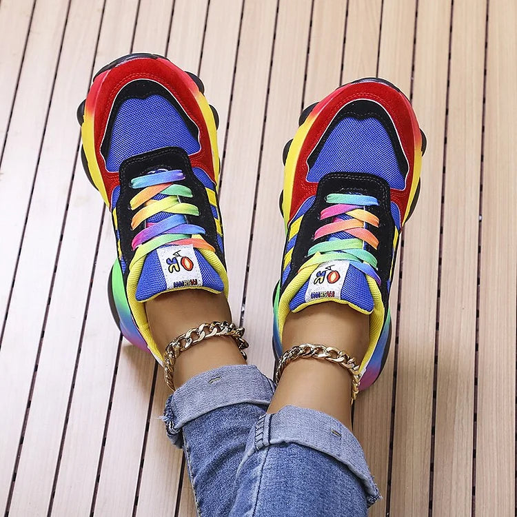 Blue and red sneakers with multicoloured laces and rainbow soles, shown from above.