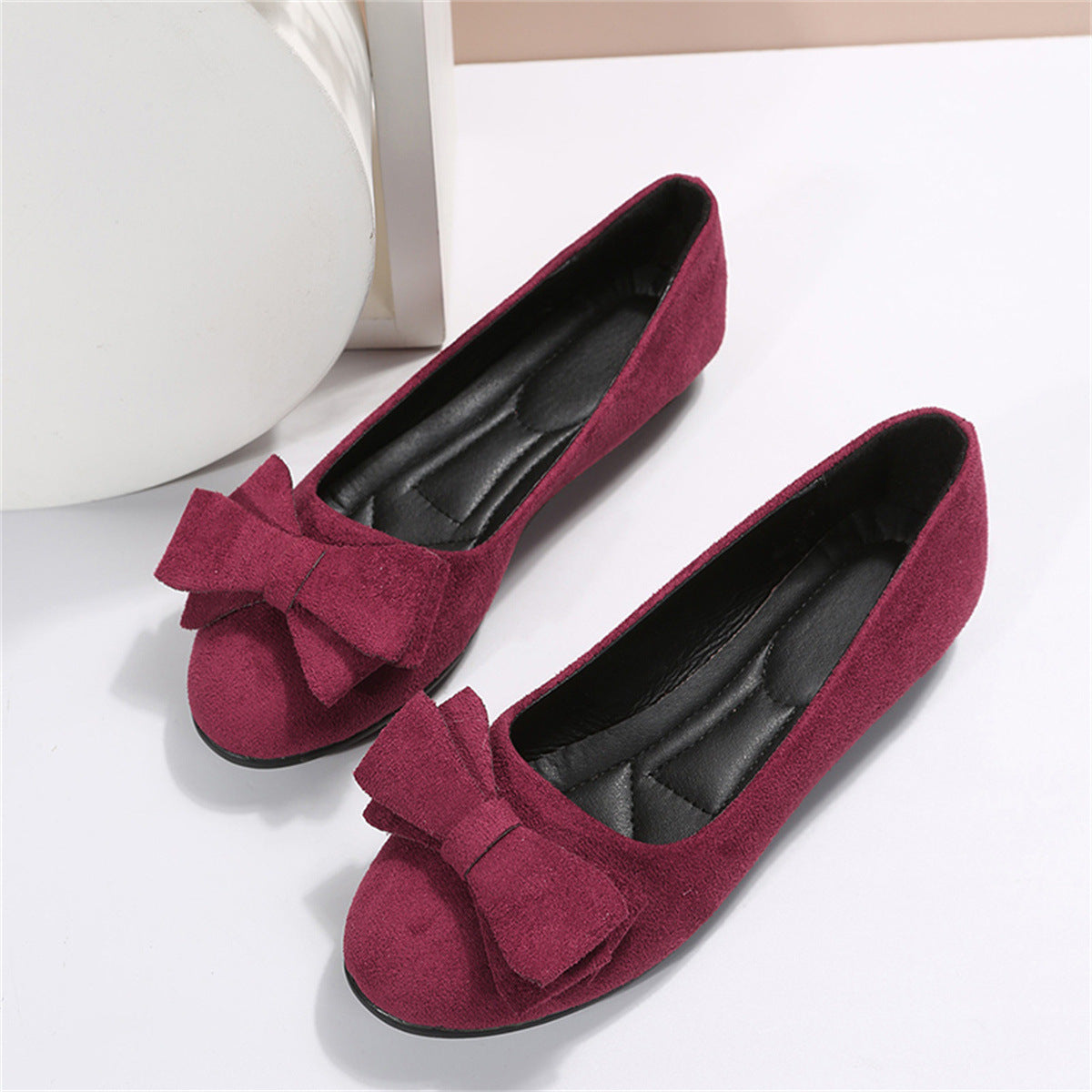 Pair of burgundy flats with rounded toes and layered bows.
