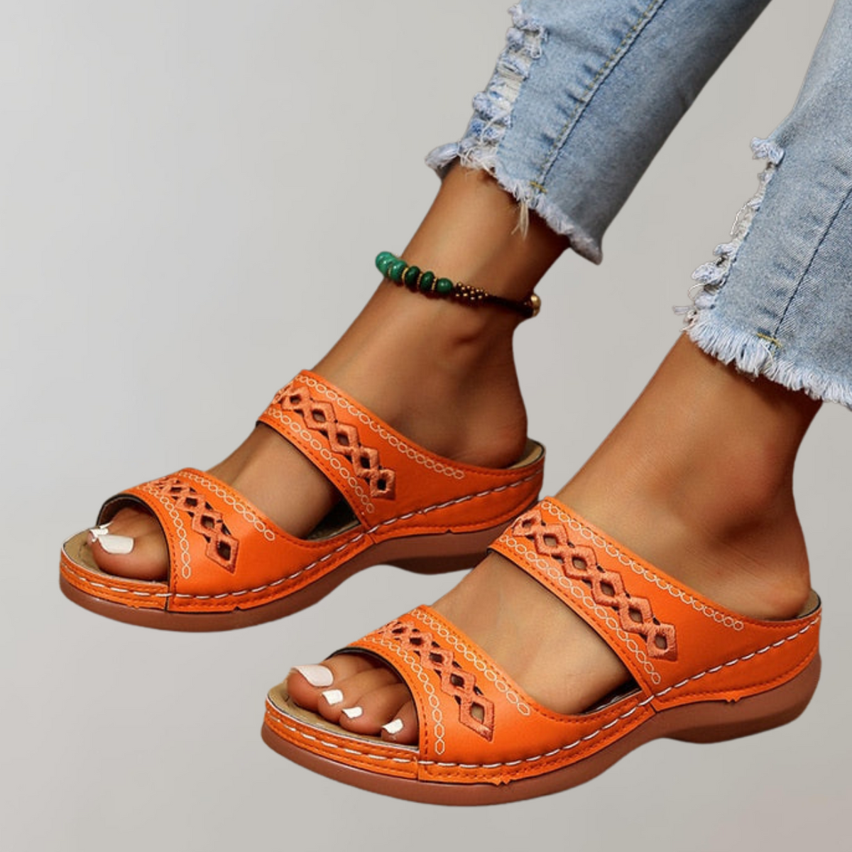 Orange sandals with two broad patterned straps and open toes.