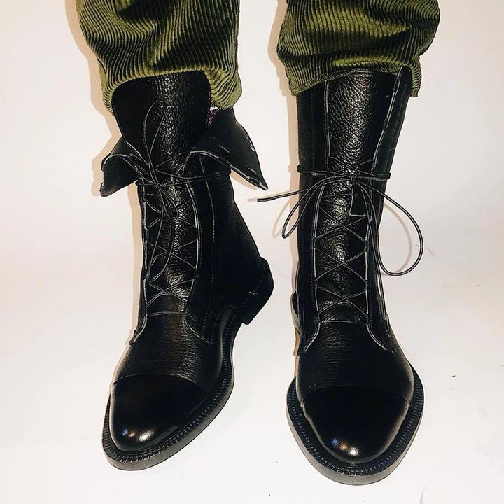 Black boots worn with green trousers, with loosened upper lacing.