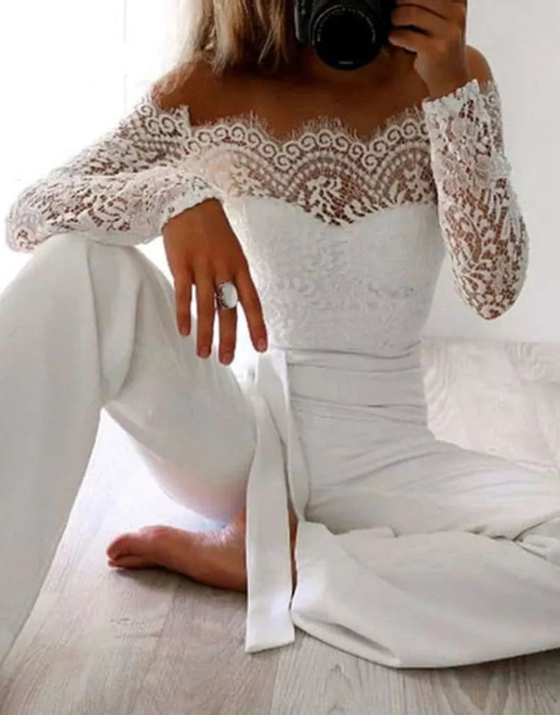 White lace jumpsuit shown seated, with a scalloped neckline and waist sash.